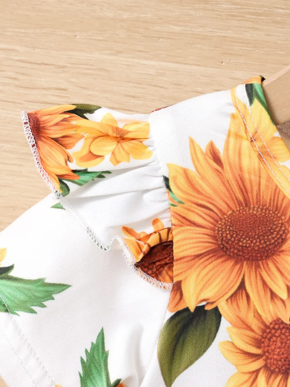 Floral fabric featuring bright sunflowers and green leaves on a white background.