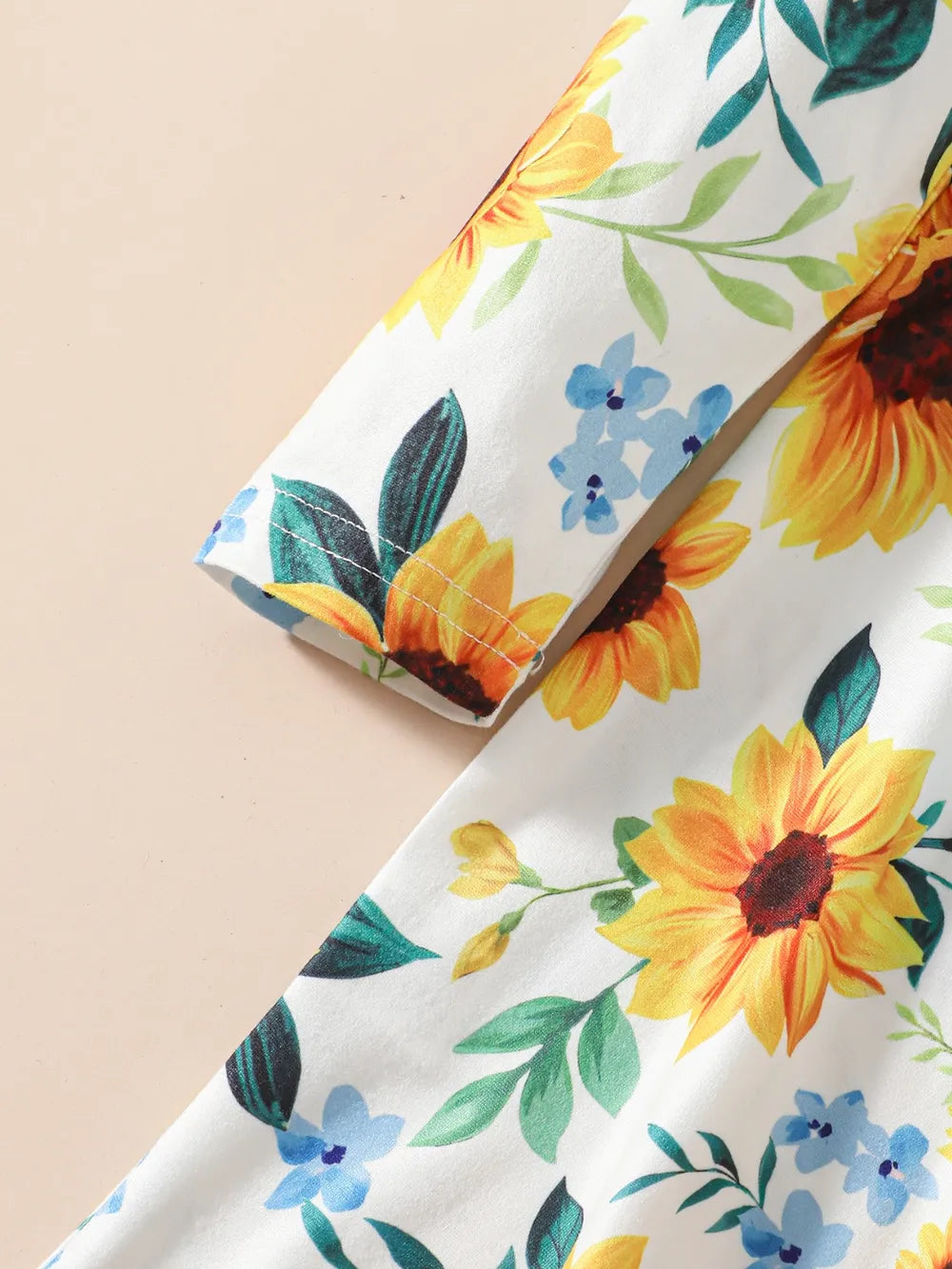 Floral fabric with vibrant sunflowers and blue flowers on a light background.