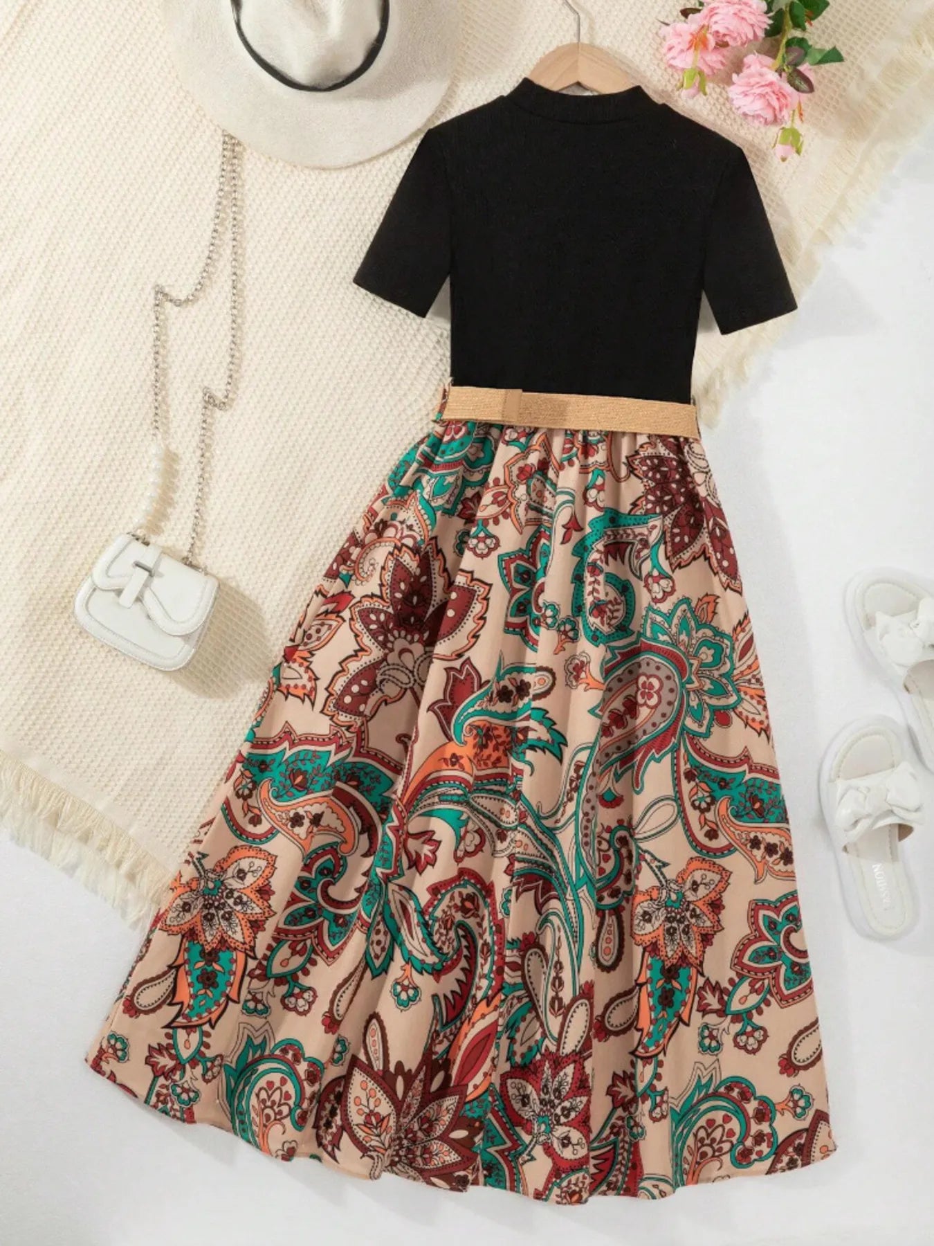 Black short-sleeve top with a paisley-print skirt, styled with a belt and accessories.