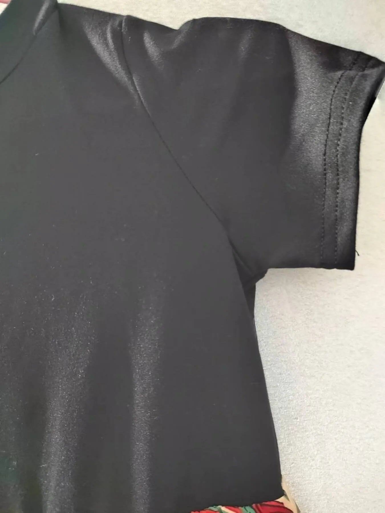 Black t-shirt with short sleeves and a smooth texture, partially cropped from the bottom.