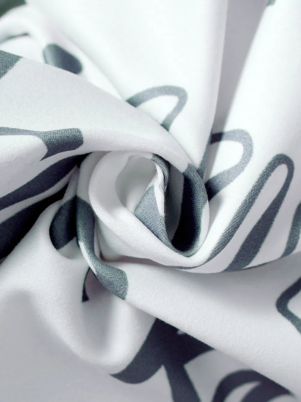 Close-up of folded fabric featuring a white background with gray abstract patterns.