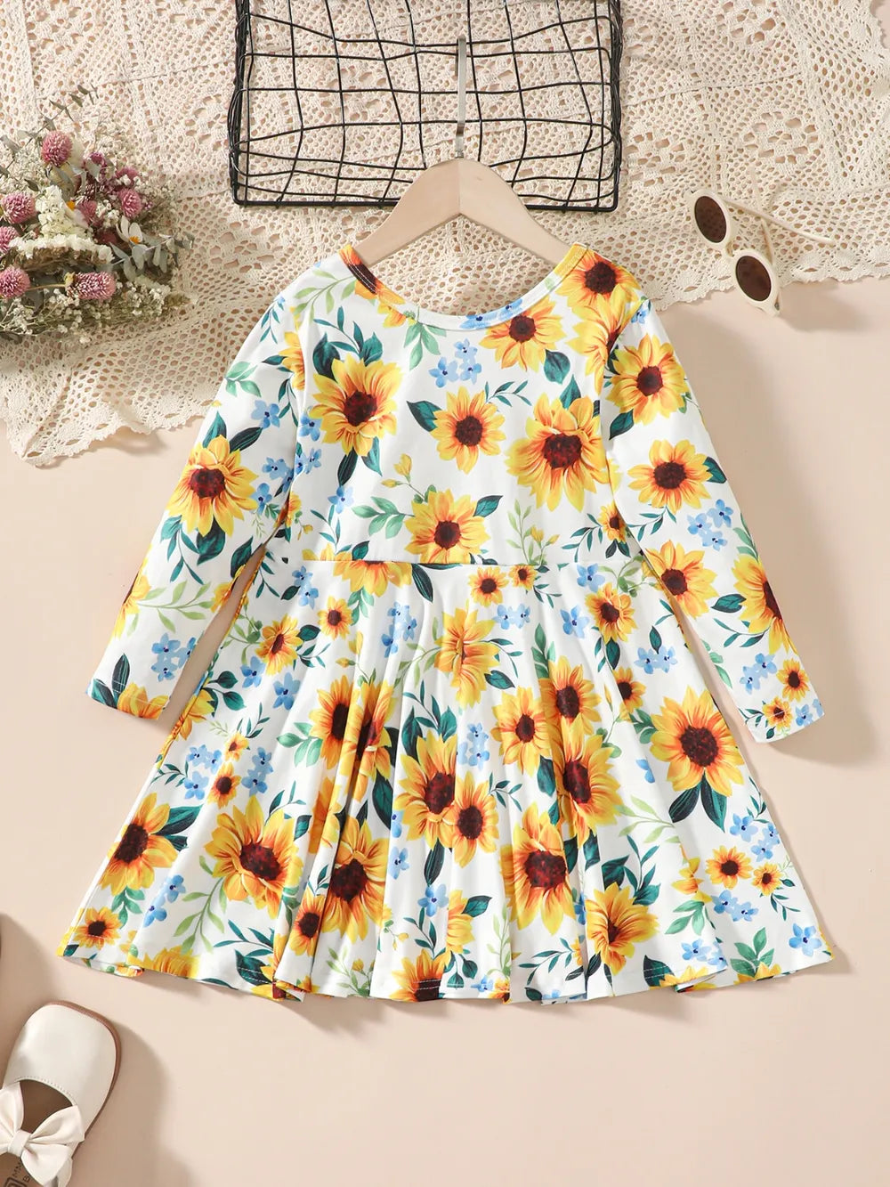 Floral long-sleeve dress featuring yellow sunflowers on a white background, displayed flat.
