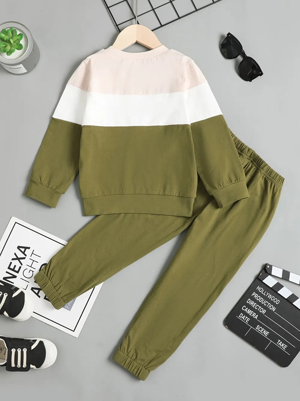 Olive green children's tracksuit with color-blocked top and black sneakers.