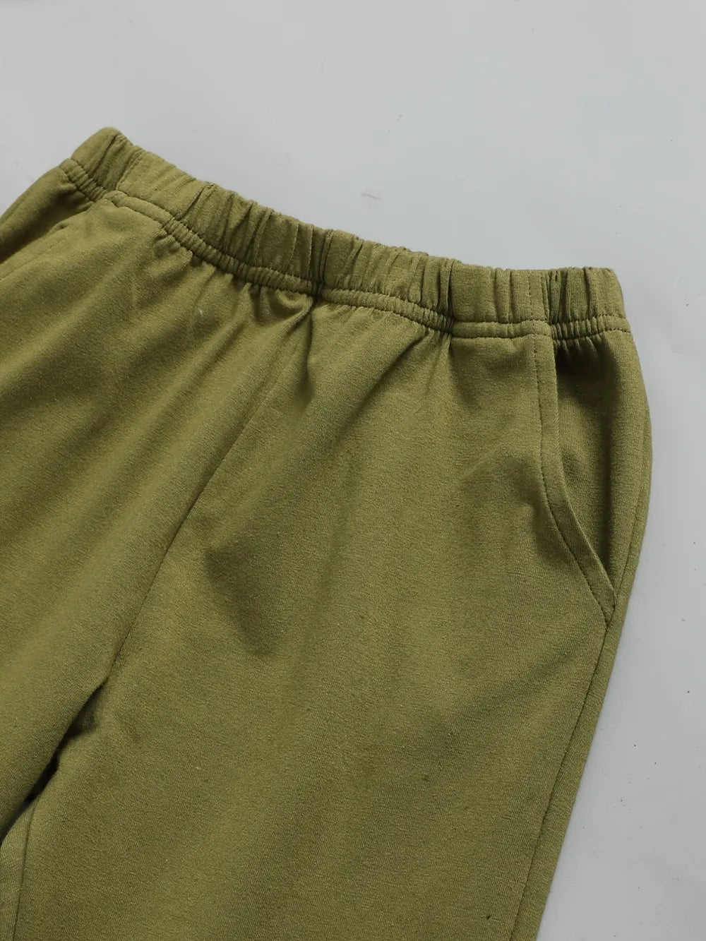 Olive green sweatpants with an elastic waistband and side pockets. Smooth fabric texture.