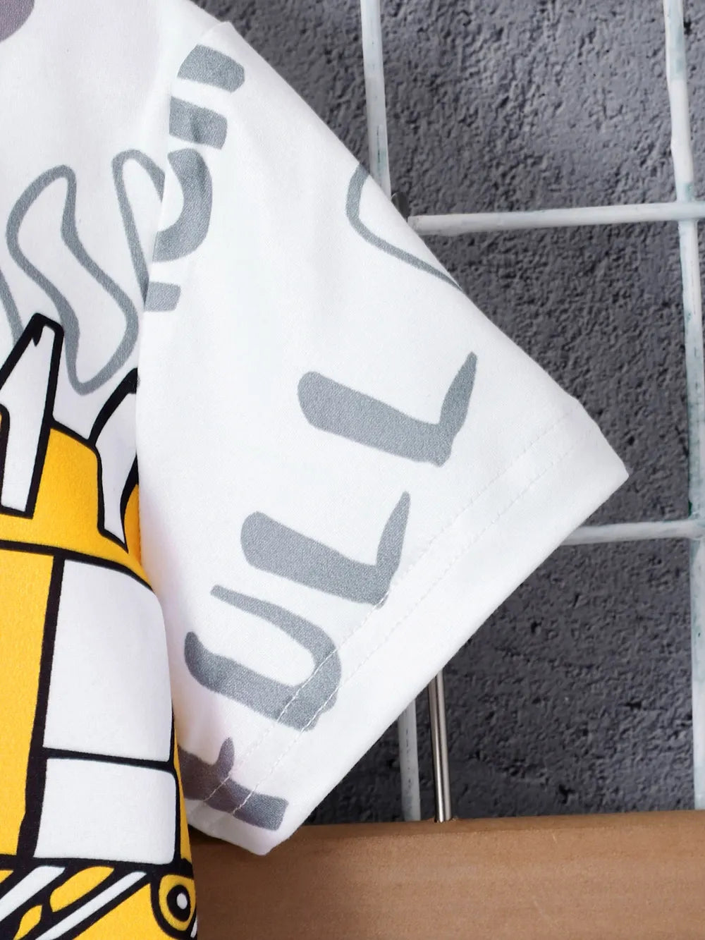 White t-shirt with playful graphics, featuring a yellow design and gray text on a textured background.