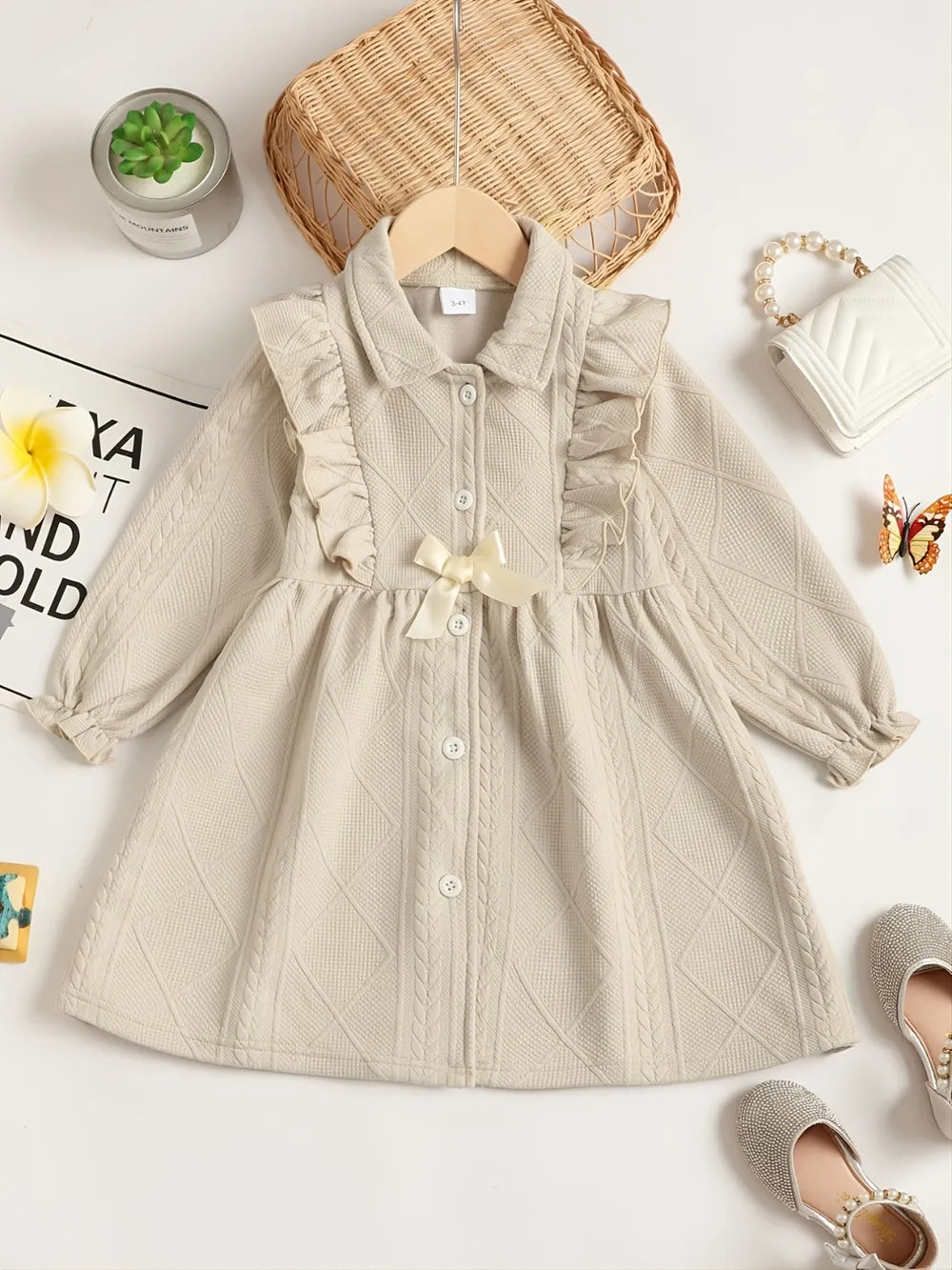 Cream-colored textured fabric with ruffled sleeve detail, paired with a soft background.
