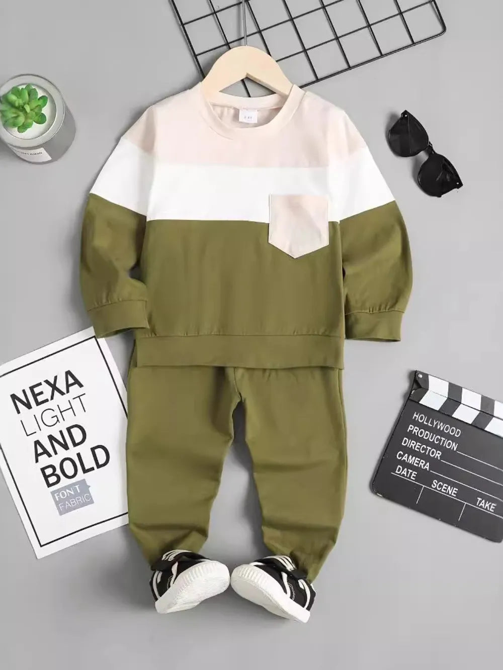 Olive green and white toddler outfit displayed with sunglasses and a film clapperboard.