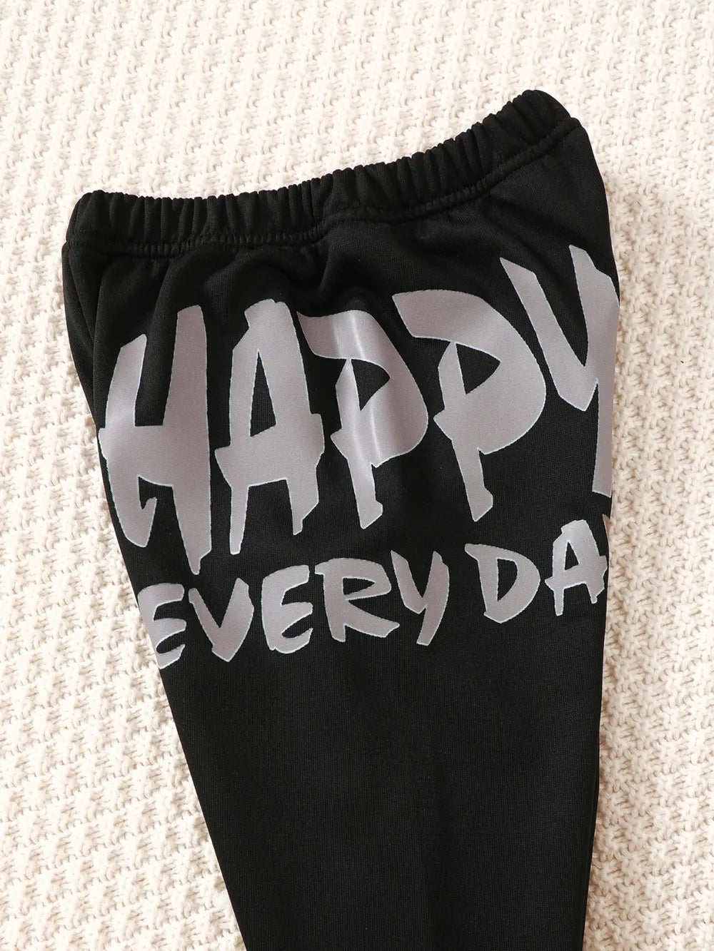 Black leggings featuring the text "HAPPY EVERY DAY" in bold gray letters.
