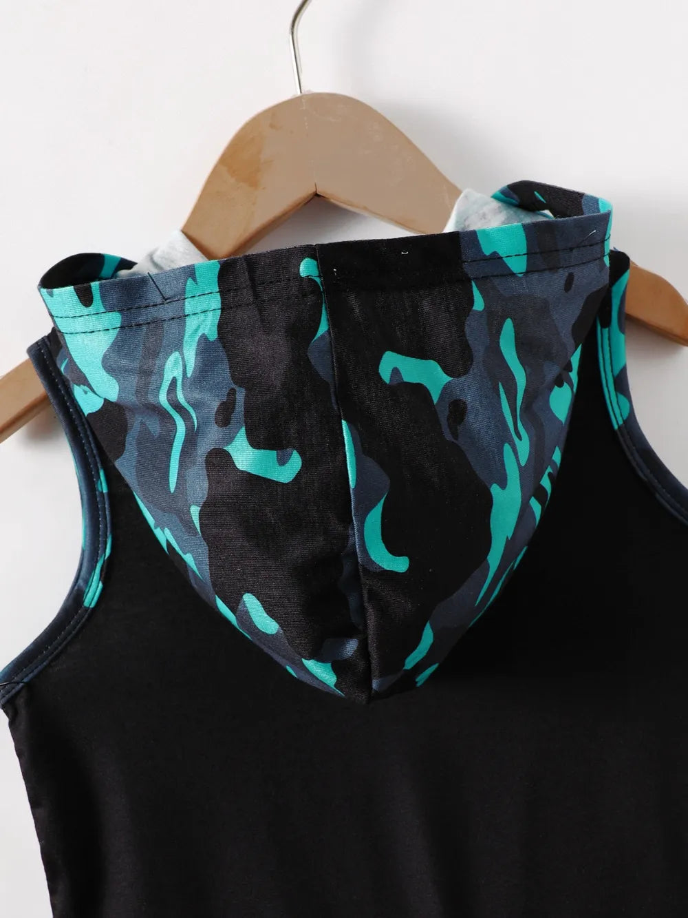 Black sleeveless hoodie with a teal and black camo-patterned hood on a wooden hanger.