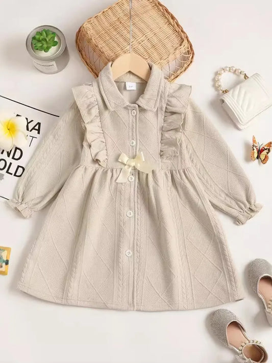 Beige dress with textured pattern, styled flat, accompanied by accessories and a plant.