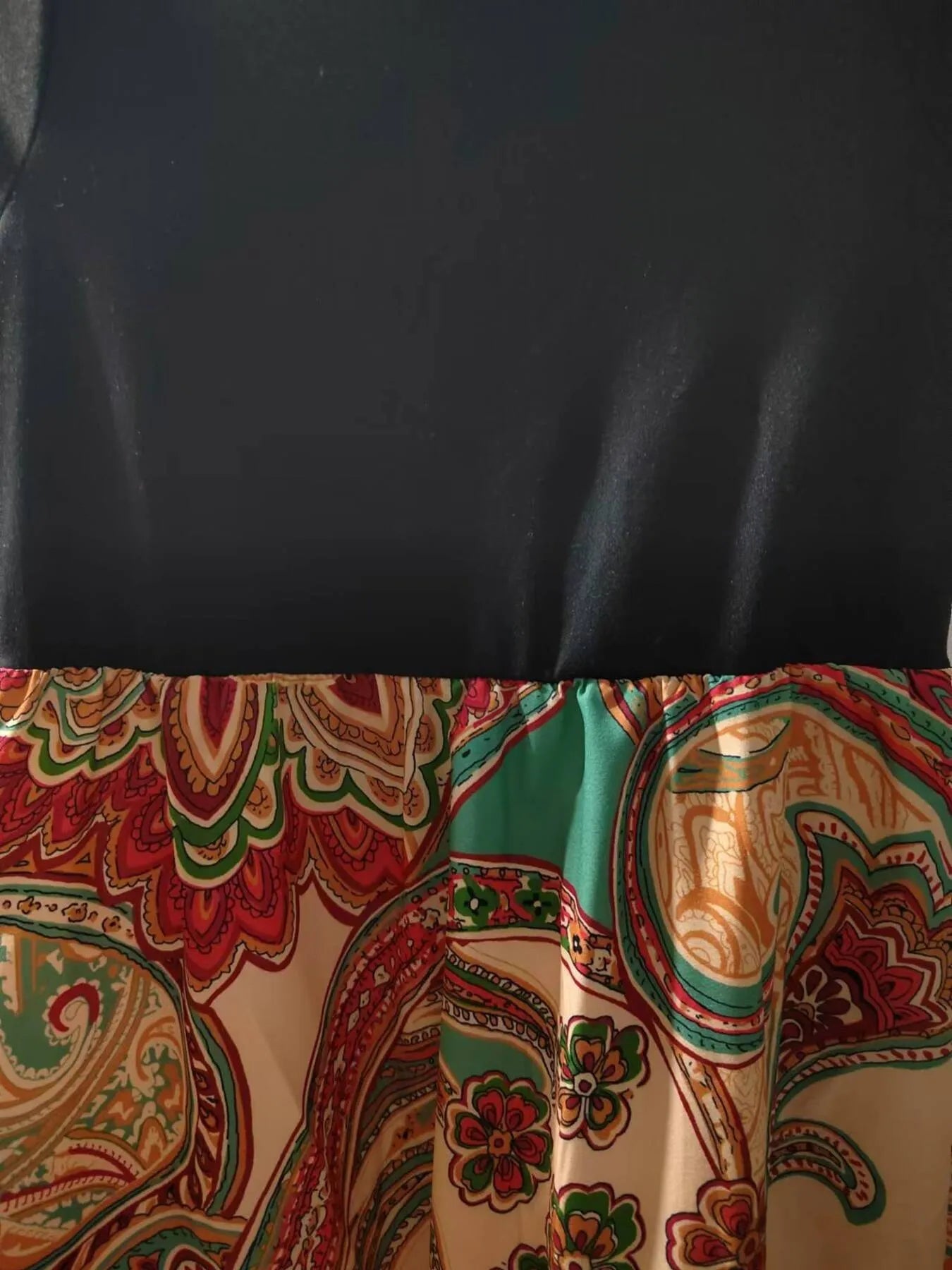 Black top with colorful paisley-patterned skirt gathered at the waist.
