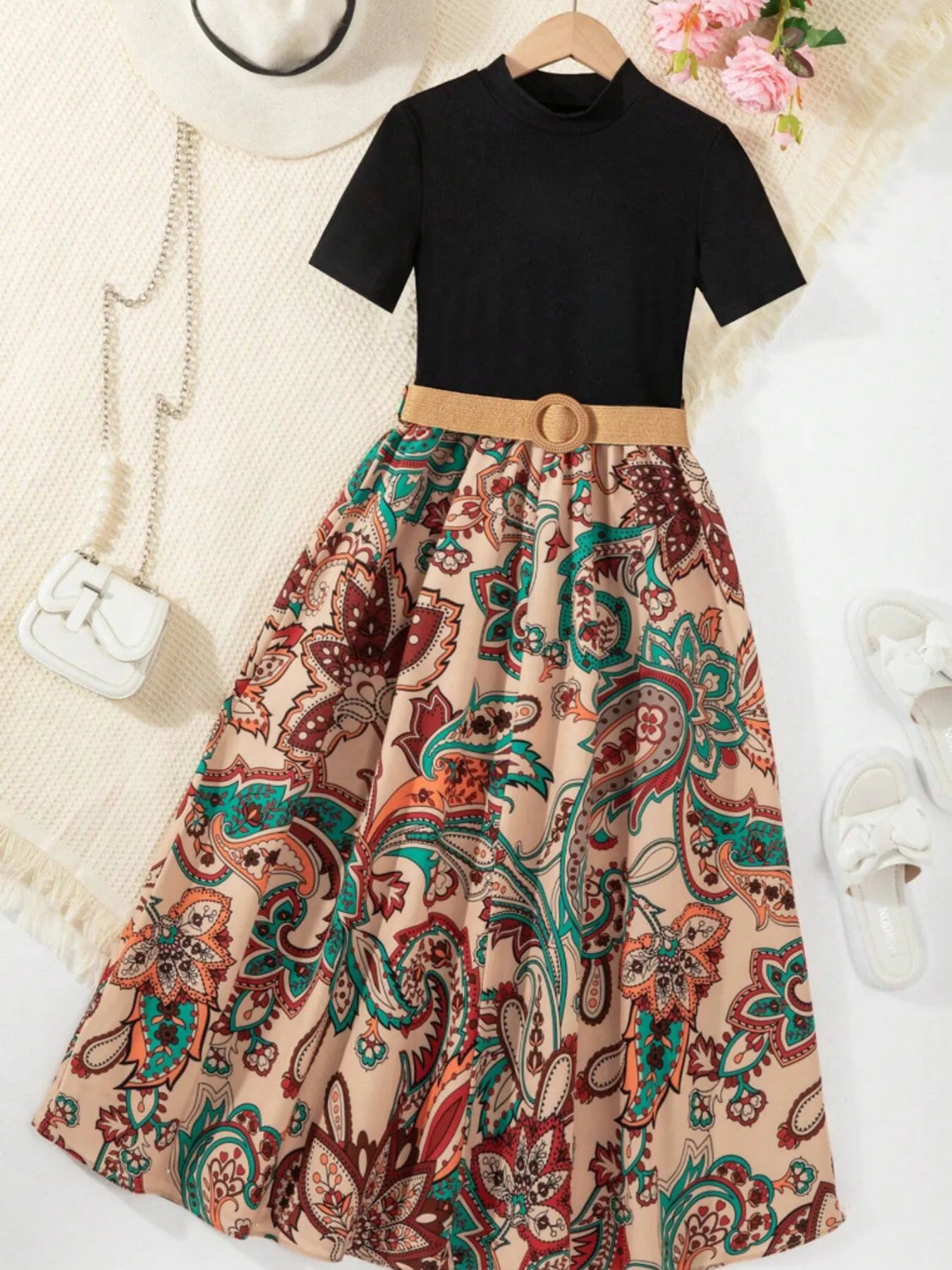 Black top with a floral maxi skirt, complemented by a belt, hat, and sandals.