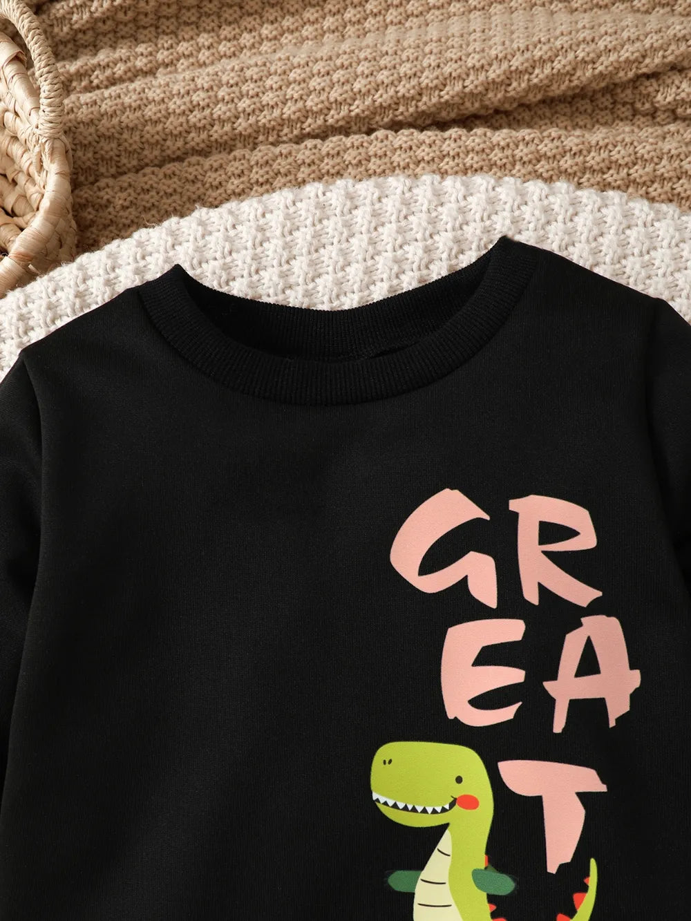 Black sweatshirt collar featuring a cartoon dinosaur and the word "GREAT" in playful typography.