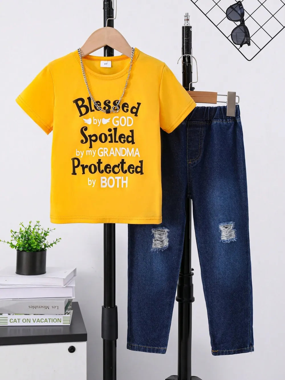 Yellow t-shirt with text, paired with distressed denim pants, displayed on a hanger.