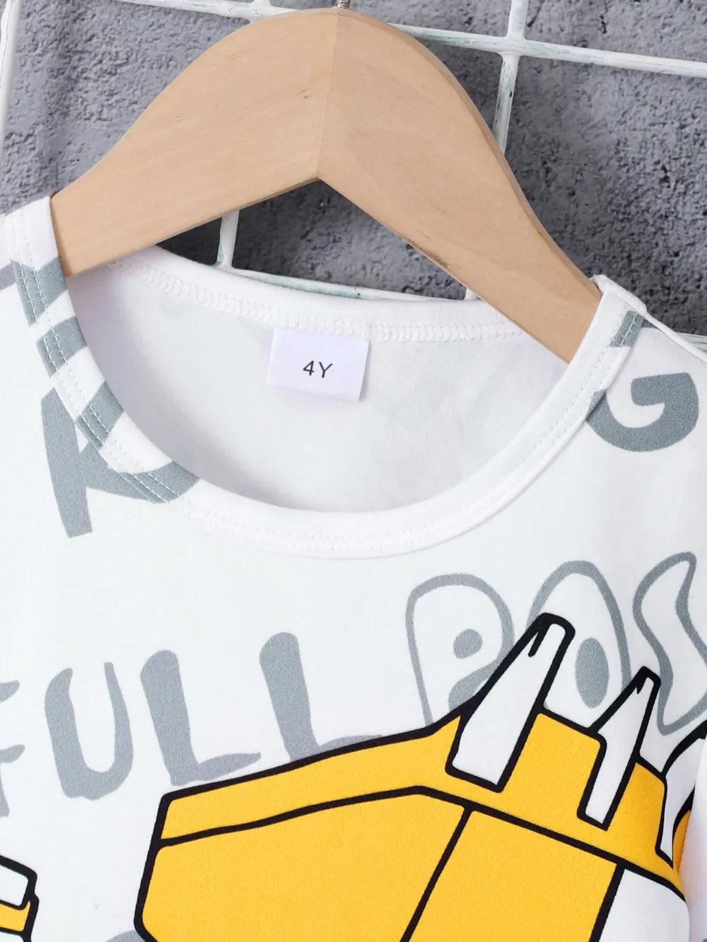 White t-shirt featuring yellow graphic design and size label "4Y" on a wooden hanger.