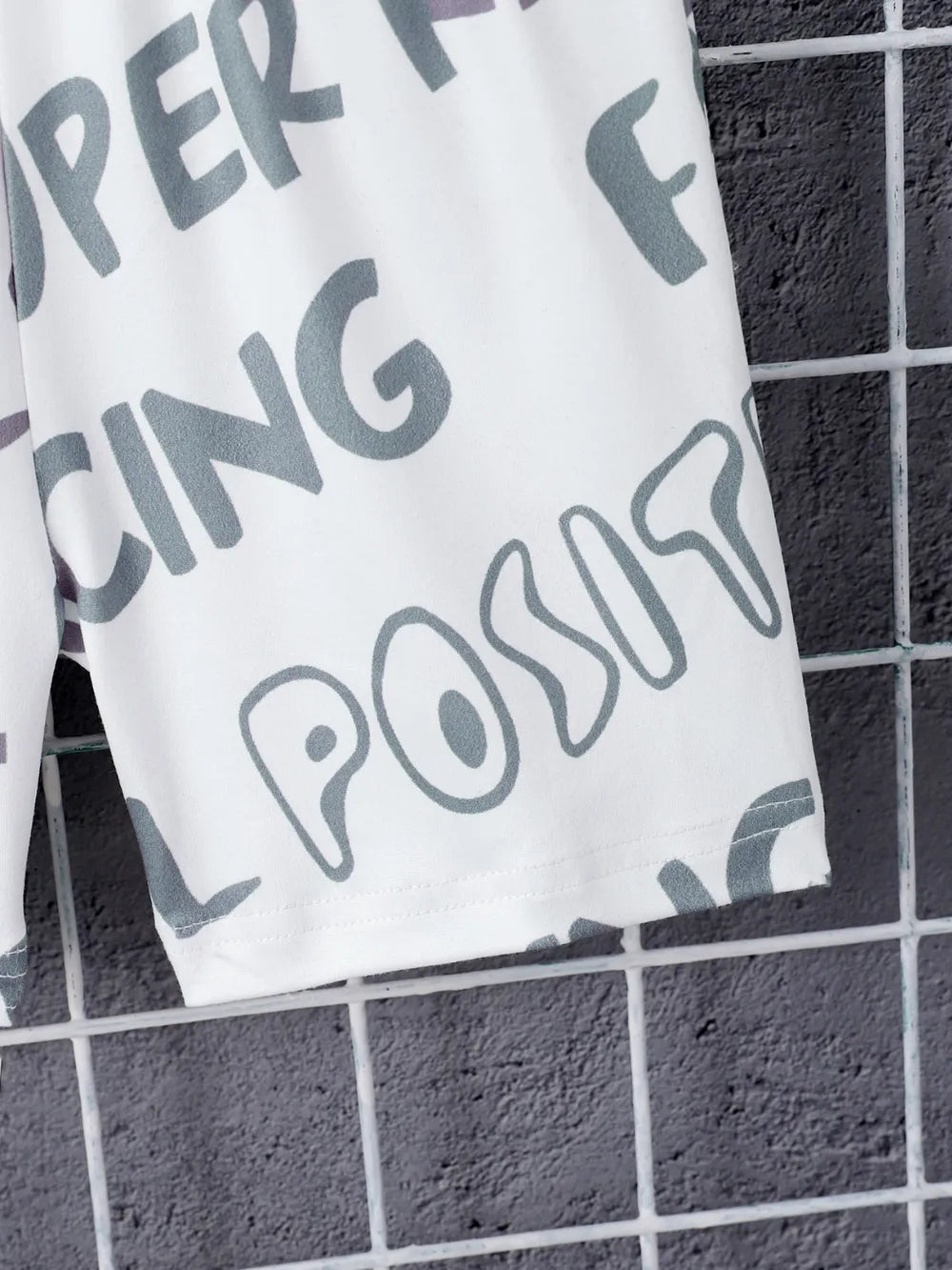 White shorts featuring large, playful grey text against a textured gray background.