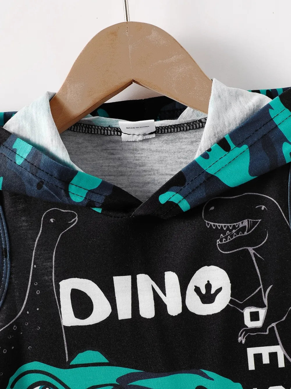 Hooded sleeveless shirt with dinosaur graphics and text on a hanger, featuring blue and black colors.