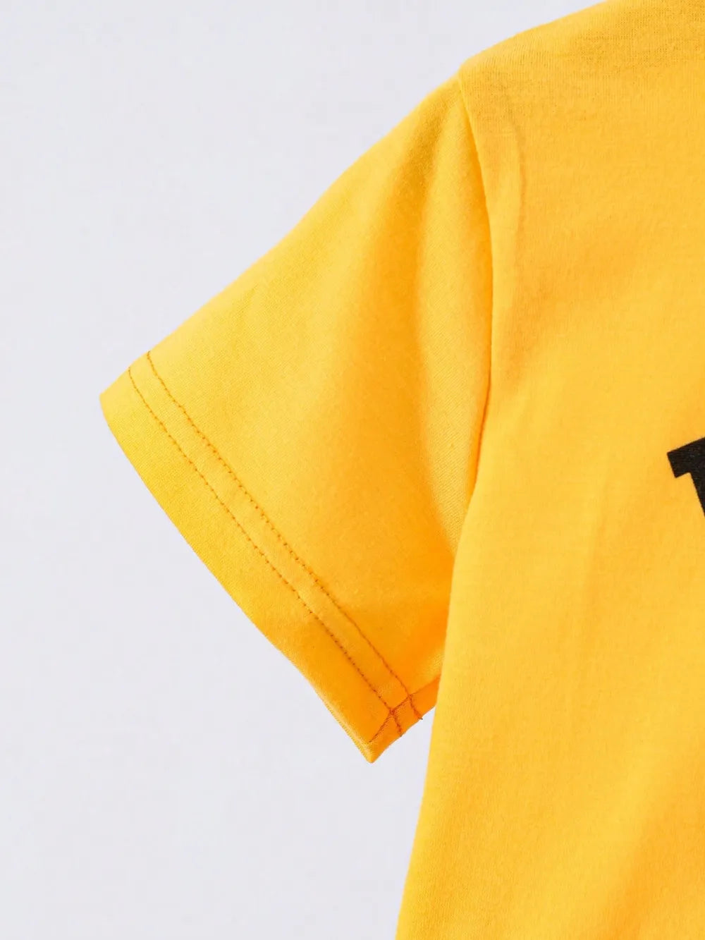 Bright yellow t-shirt sleeve showing neat stitching and fabric texture against a light background.