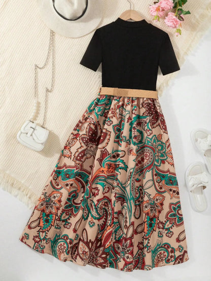 Black short-sleeve top with a paisley-print skirt, styled with a belt and accessories.