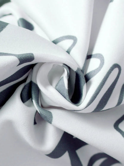Close-up of folded fabric featuring a white background with gray abstract patterns.