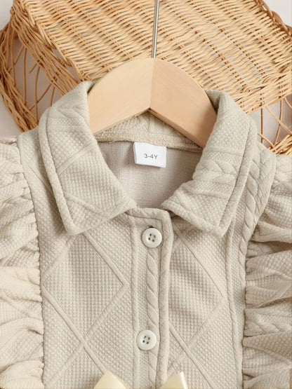 Light beige children's jacket featuring a textured pattern, buttons, and ruffled sleeves.