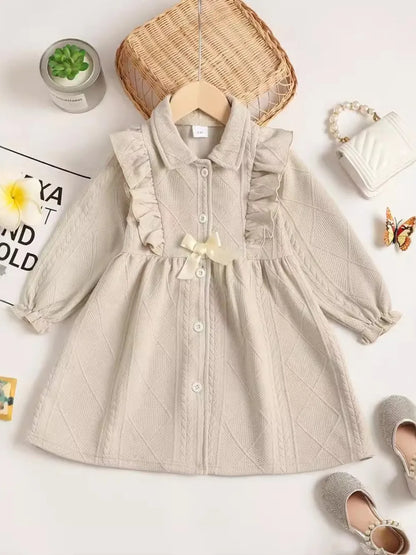 Beige dress with textured pattern, styled flat, accompanied by accessories and a plant.