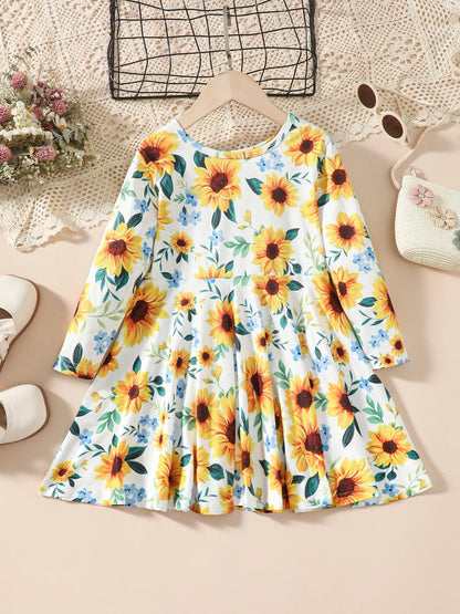 Floral dress with sunflowers and blue flowers, displayed on a hanger against a light background.