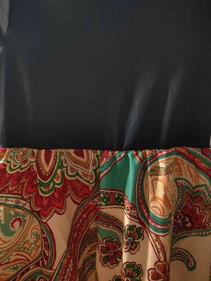 Black top with colorful paisley-patterned skirt gathered at the waist.