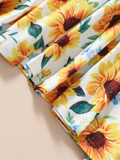 Bright fabric featuring large sunflowers and blue flowers with green leaves against a white background.